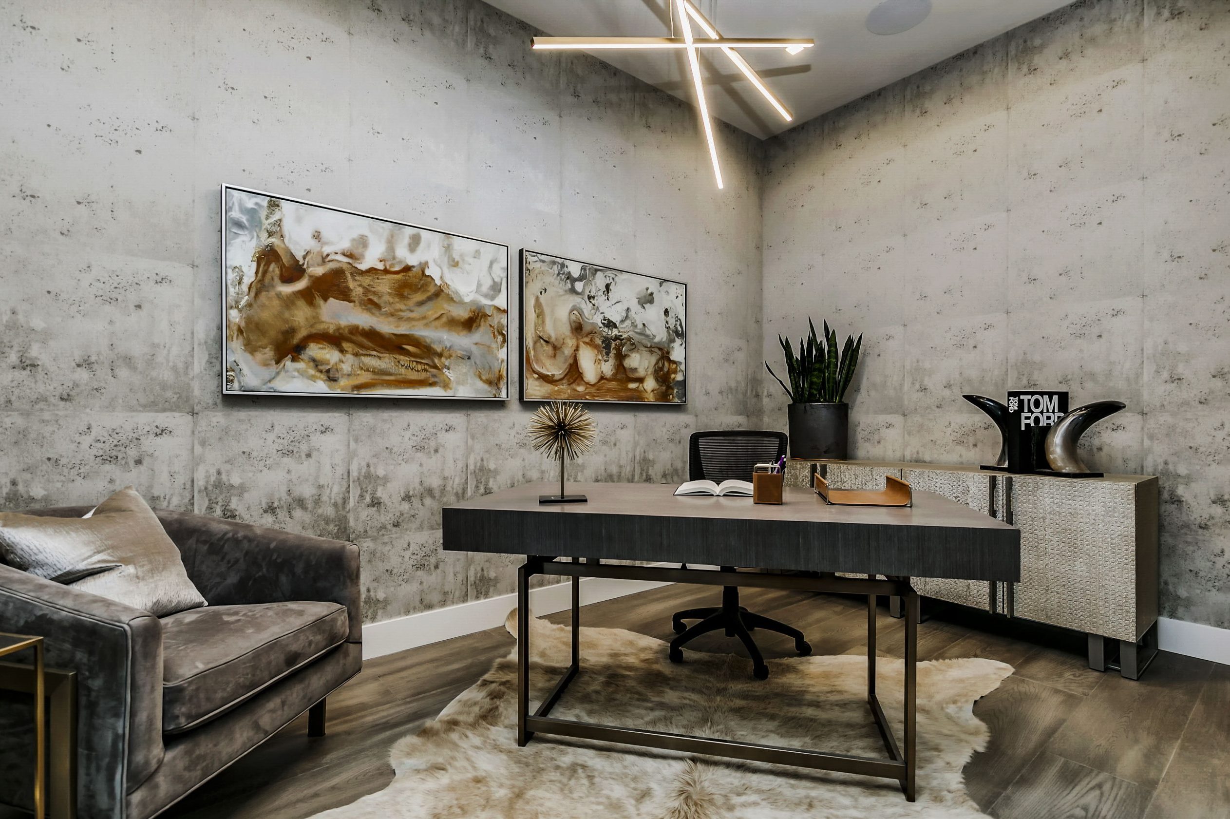 Modern office space with industrial wallpaper, rich warm gray furniture and a contemporary chandelier