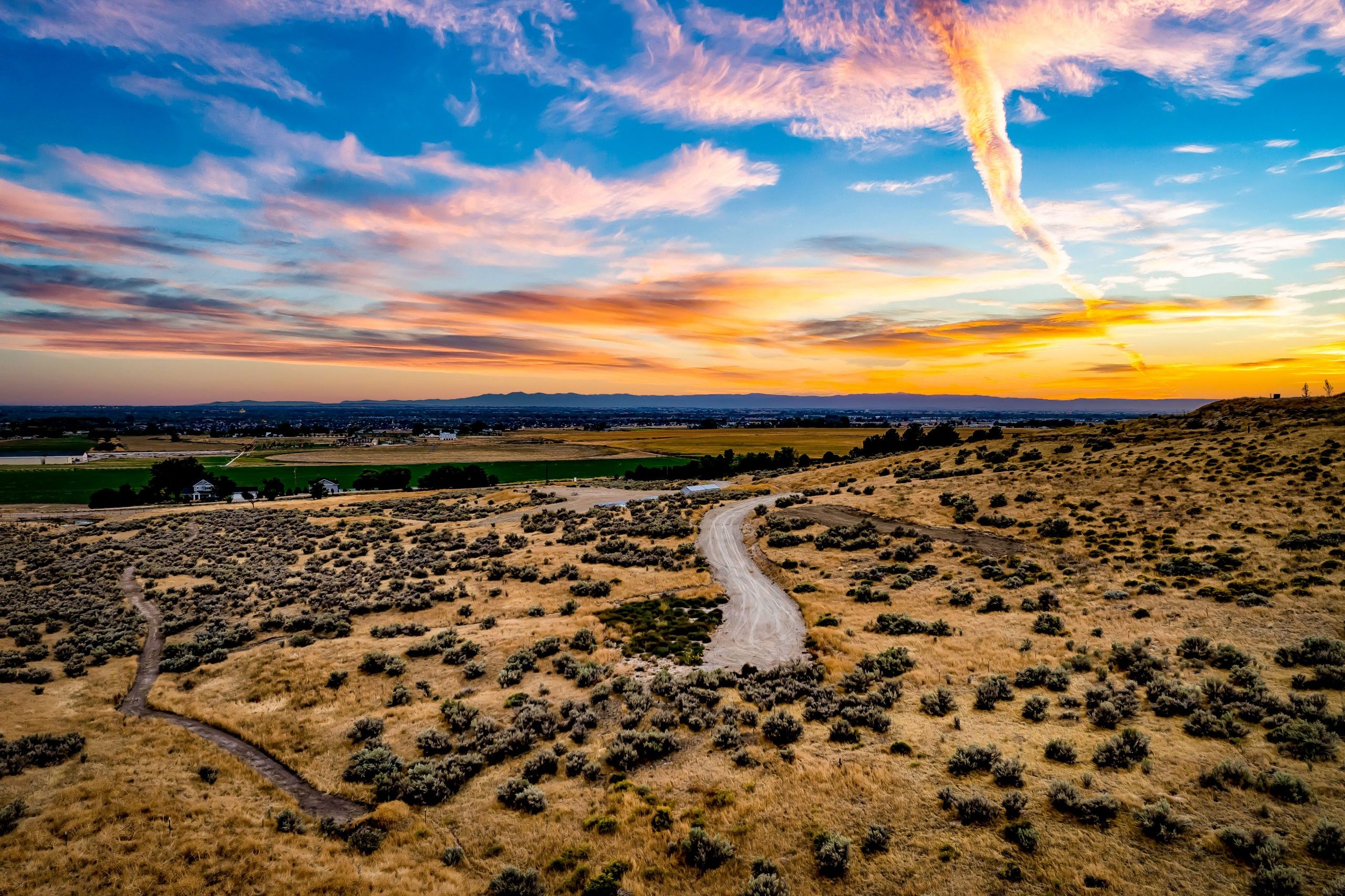 Aerial view of lot 1 in Eagle's Elkhorn Reserve community at dusk. Picturesque sunset sky with warm colors above the foothills.