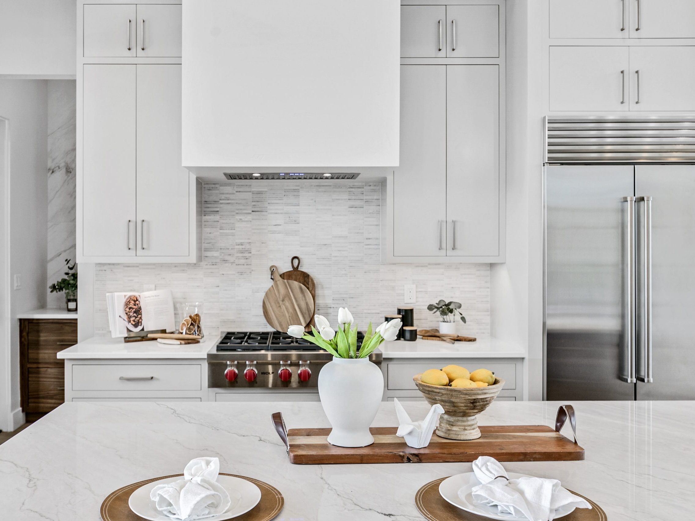 Light and bright modern luxury kitchen in Eagle, Idaho. Stainless steel appliances, light gray cabinetry, and white marble countertops.