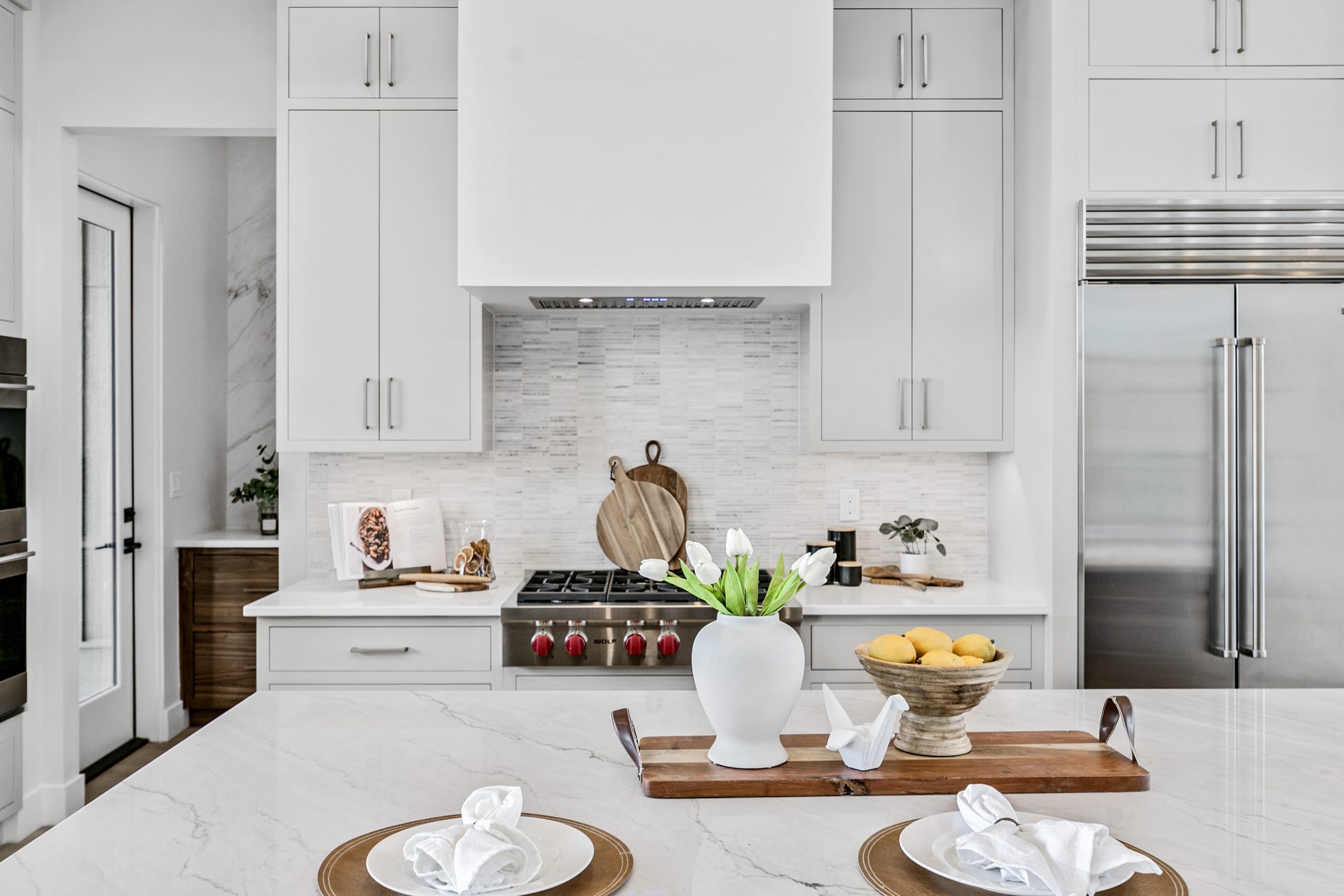 Light and bright modern luxury kitchen in Eagle, Idaho. Stainless steel appliances, light gray cabinetry, and white marble countertops.